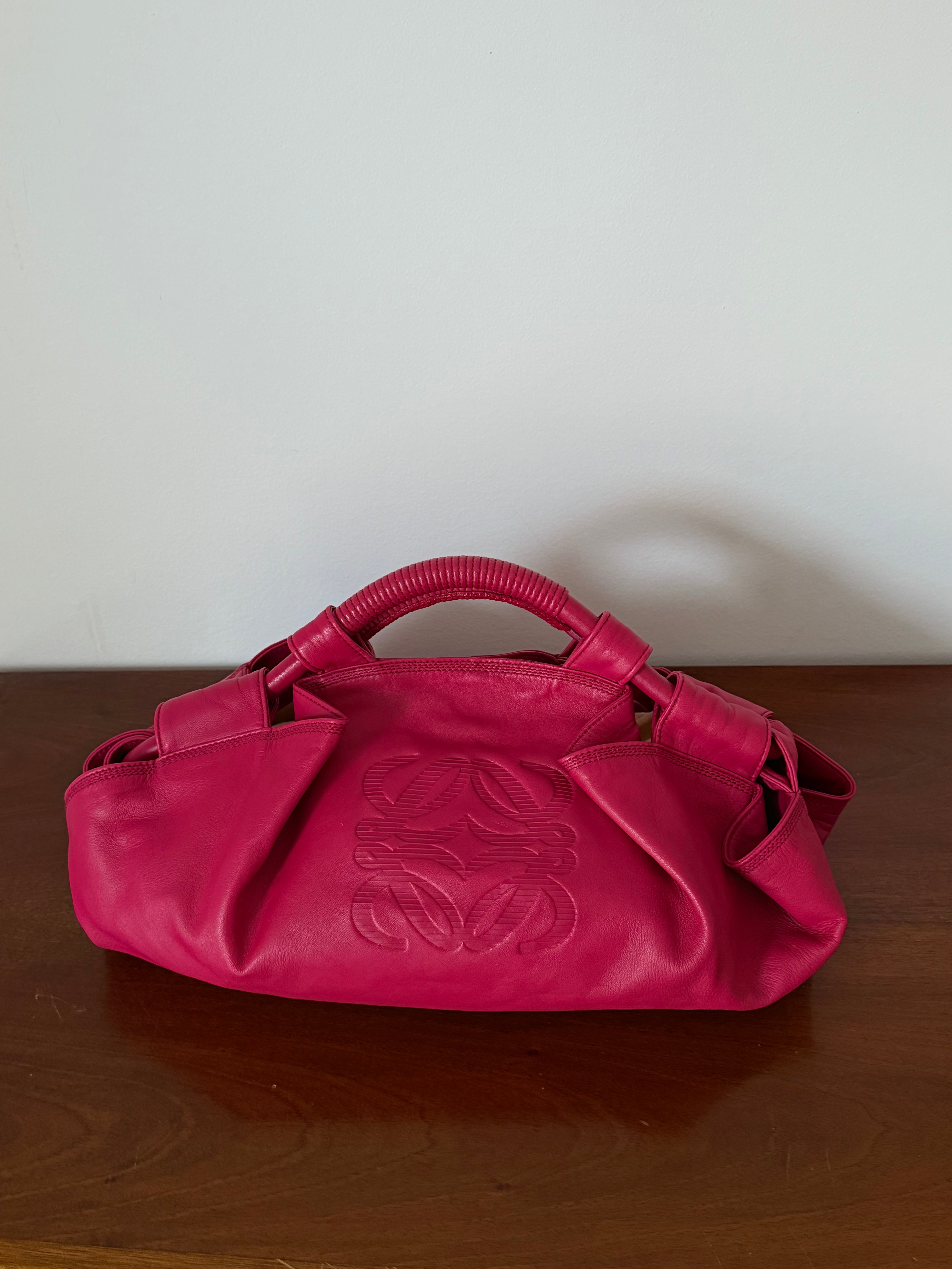 Pink handbag with a brand logo on a wooden surface