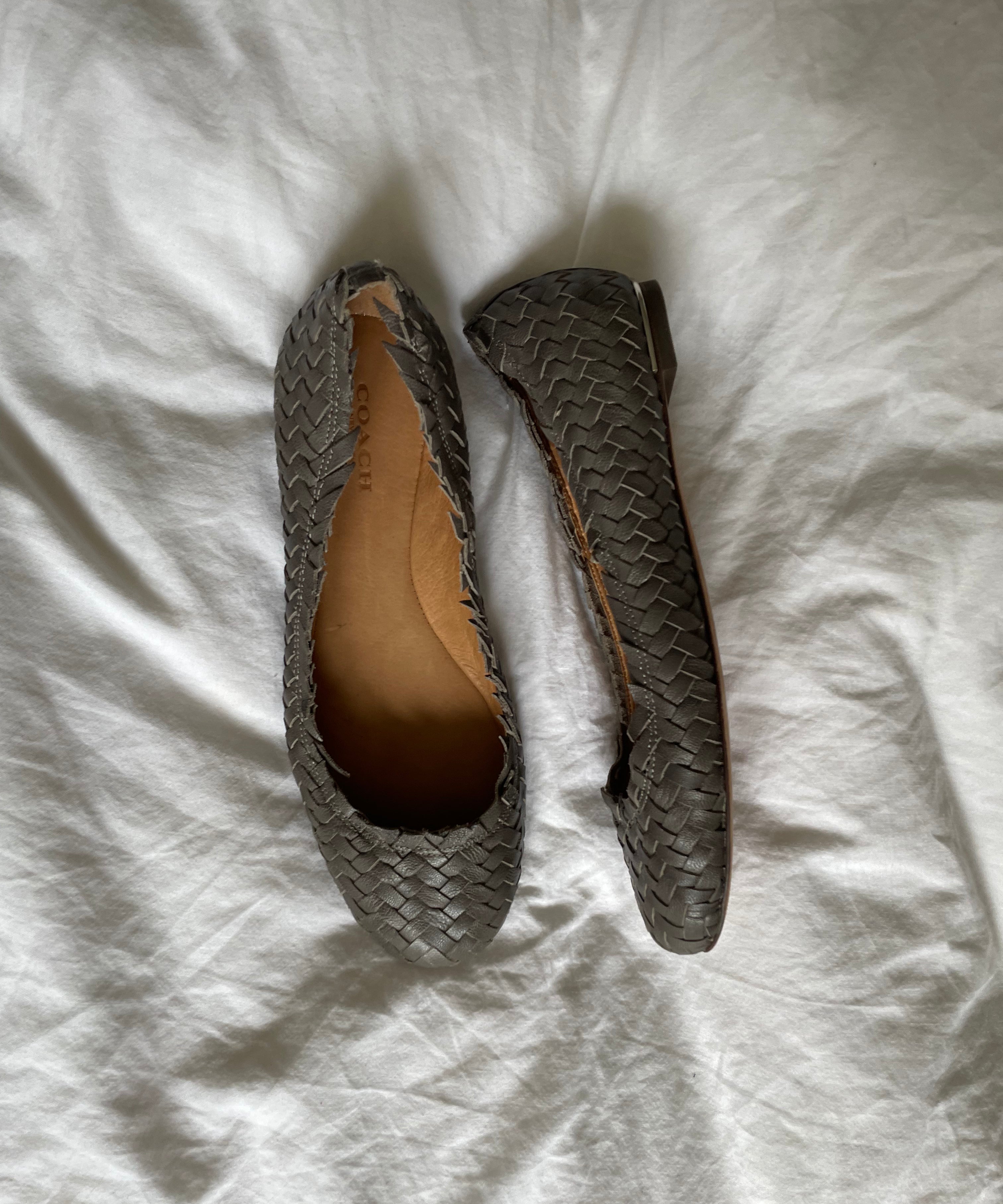 Coach woven leather ballet flats in grey with a subtle silver edge. They’re in excellent condition and show little to no signs of visible wear.