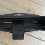 This vintage Coach bag from year 2000 is crafted from black leather and denim. It comes with an adjustable strap and magnetic closure, along with both an interior and exterior pocket. The bag is in great condition.